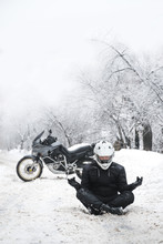 Rider Man And Adventure Motorcycle. Snowy Day. Meditating In The Lotus Position That Used To End The Winter. Travel Tour, Active Life Style Concept. Winter Clothes, Equipment, Vertical Photo