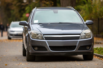 Wall Mural - Gray shiny car parked in quiet area on asphalt road on blurred bokeh background on bright sunny day. Transportation and parking concept.