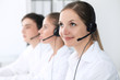 © rogerphoto - Call center operators at work. Focus at beautiful business woman in headset