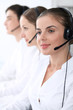 © rogerphoto - Call center operators at work. Focus at beautiful business woman in headset