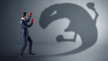 Businessman With Boxing Glove Fighting With A Big Monster Shadow
