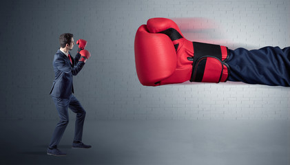 Tiny businessman fighting with boxing gloves
