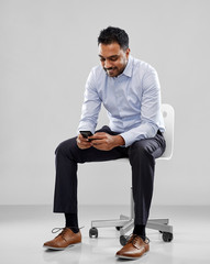 Sticker - business, furniture and people concept - smiling indian businessman sitting on office chair over grey background