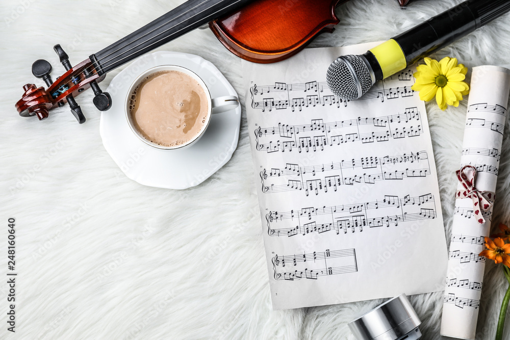 Composition with violin, cup of coffee and music sheets on fluffy plaid