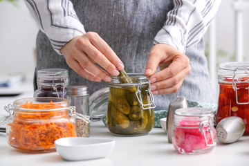 Wall Mural - Woman with glass jar of fermented cucumbers in kitchen