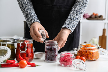 Woman preparing beetroot for fermentation at table in kitchen