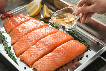 Wall Mural - Woman pouring raw salmon fillet with oil