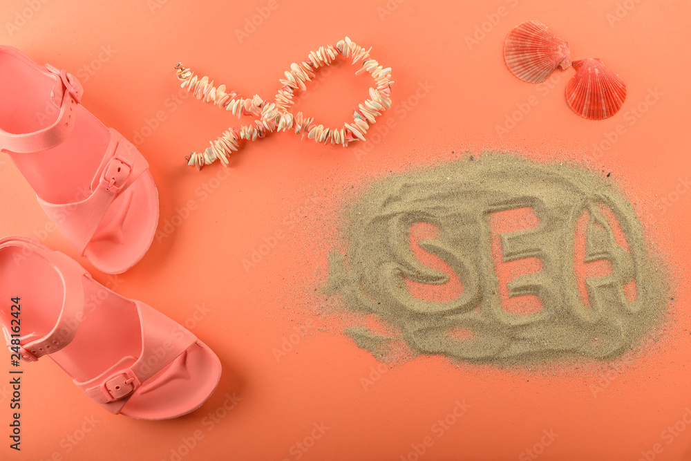 Summer composition with word SEA and beach accessories on coral background