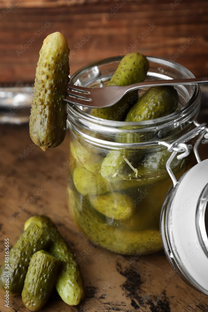 Jar with tasty fermented cucumbers on metal tray