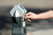 Adult's hand feeding quarters to a parking meter for extra time