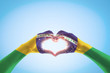 Brazil flag on people hands in heart shape for Brazilian Valentine's Day and national holiday celebration isolated on blue sky background