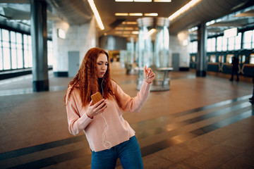 Positive redhead young female dancing in subway