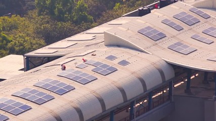 Wall Mural - Workmen installing solar panels on the roof of metro station in Noida