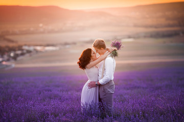 Wall Mural - Young couple in love bride and groom, wedding day in summer. Enjoy a moment of happiness and love in a lavender field. Bride in a luxurious wedding dress.