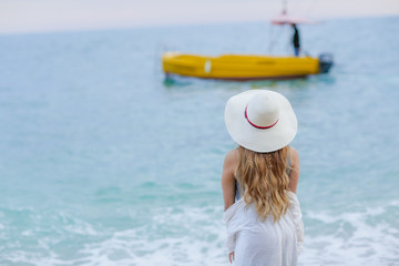 girl wearing a sea cap standing on the beach, clear sky, beautiful sea for relax.