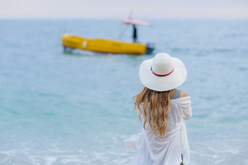 girl wearing a sea cap standing on the beach, clear sky, beautiful sea for relax.