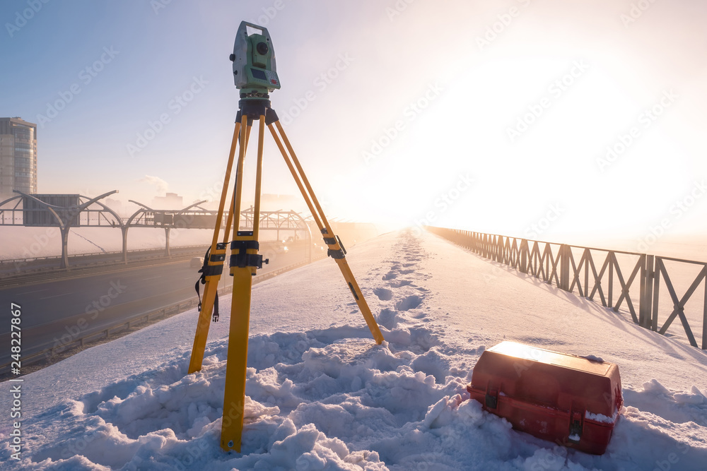 Theodolite. Topographic equipment. Theodolite stands on a tripod. Topographical measurements. Measurement of soil creep. Construction works. Construction measurements. The work of the tapographer. - obrazy, fototapety, plakaty 
