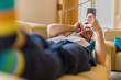 © qunica.com - Young guy lying at the couch and hold mobile