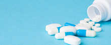 Close Up Pills Spilling Out Of Pill Bottle On Blue Background. Medicine, Medical Insurance Or Pharmacy Concept