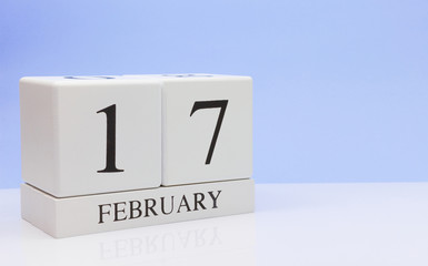 February 17st. Day 17 of month, daily calendar on white table with reflection, with light blue background. Winter time, empty space for text