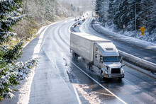 Big Rig Semi Truck With Semi Trailer Driving On Winter Snowy Highway With Wet Melting Snow Surface