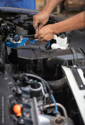 Car Service By An Auto Mechanic In Garage Fixing A Battery With Car Service By An Auto Mechanic In Garage Fixing A Battery With Wrench