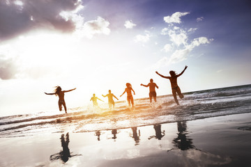 Poster - Group of happy peoples runs and jumps at sunset sea beach. Tropical tourism concept