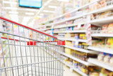 Fototapeta  - Empty shopping cart with abstract blur supermarket discount store aisle and product shelves interior defocused background