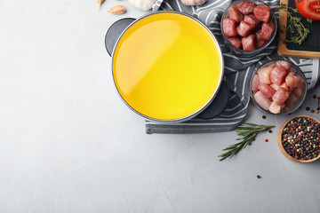 Flat lay composition with fondue pot, meat and space for text on table