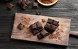 Pieces of black chocolate on wooden table, top view