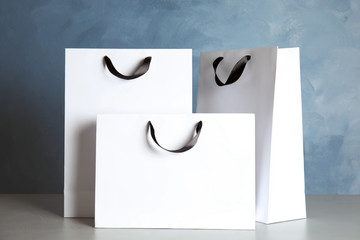 Poster - Paper shopping bags on table against color background. Mock up for design