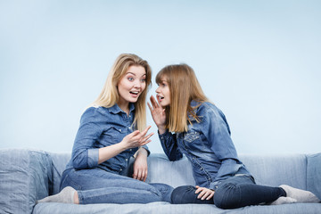 Two happy women friends wearing jeans outfit talking