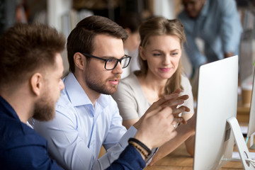 Serious employees working together discussing computer task in office