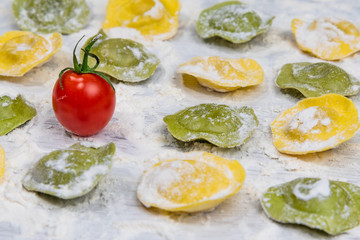 Wall Mural - Homemade fresh Italian ravioli pasta on white wood table  with flour close-up.