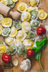 Wall Mural - Homemade fresh Italian ravioli pasta on wood table  with flour, basil,tomatoes,background,top view.