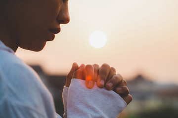 Woman praying in the morning on the sunrise background. Christianity concept. Pray background. Faith hope love concept.