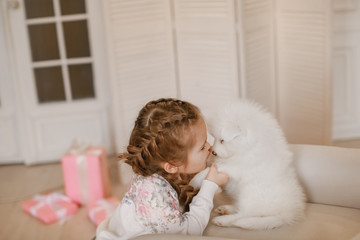 Wall Mural - Child girl is holding puppy on her hands near pink the gift boxes