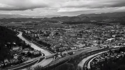 Sticker - Celje, Slovenia. Car traffic in Celje, Slovenia. Bridge over the Savinja river. Aerial view of city historical center from the castle. Time-lapse during the cloudy day with mountains. Black and white