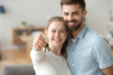 Happy young married family couple holding keys to new flat