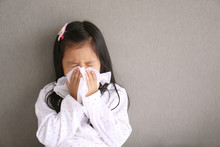 Asian Child Or Kid Girl Sick With Sneezing On Nose And Cold Cough On Tissue Paper Because Weak Or Virus And Bacteria From Dust Weather And Kindergarten And Pre School For Medical Background Gray Space