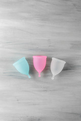 Wall Mural - Three menstrual cups on grey wooden background