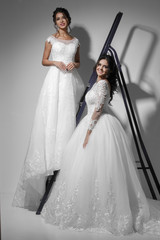 Wall Mural - Two beautiful slim  young brides wearing wedding white dress. Studio shot