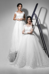 Wall Mural - Two beautiful slim  young brides wearing wedding white dress. Studio shot