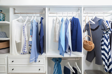 beach blue clothes and windsurf suit hanging in white wardrobe at home