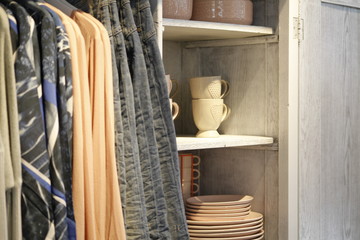 Close up of a vintage cabinet with colorful clothes and tableware