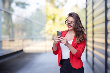 Wall Mural - Long hair beautiful business woman in red suit reading text message on mobile phone