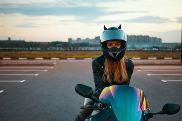 Urban modern lifestyle, extreme sports, speed and adrenaline concept. Attractive blonde girl waiting for friends to ride motor bikes around night city, copyspace pavement for your promotional content