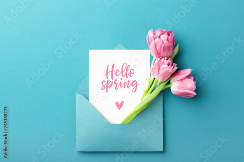 Three pink tulips in turquoise envelope on turquoise background with inscript...