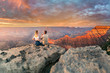 Man and woman sit on the edge of the rim having great conversation during the Grand Canyon sunset