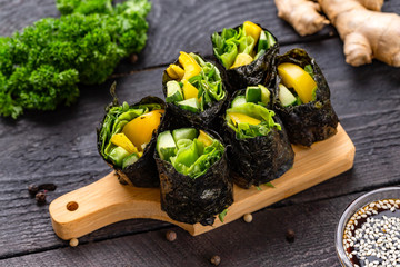 Set of healthy vegetarian vegetables sushi rolls with cucumber, pepper and green salad at decorated wooden table background.